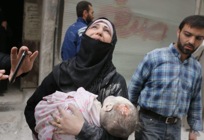 หญิงซีเรียแหงนหน้ามองฟ้าเหมือนจะถามว่า ทำไมลูกจึงมีชีวิตสั้นเช่นนี้ / AFP PHOTO / THAER MOHAMMED