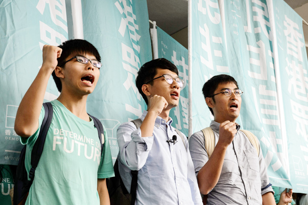 Leaders of Hong Kong's "Umbrella Revolution" (L to R) Joshua Wong, 19, Nathan Law, 23, and Alex Chow, 25, shout slogans upon their arrival outside the Eastern Court in Hong Kong on August 15, 2016. Three leaders of Hong Kong's "Umbrella Revolution" are facing possible jail sentences on August 15 over protests that sparked massive rallies in 2014, as fears grow that Beijing is closing its grip on the city.  / AFP PHOTO / ANTHONY WALLACE