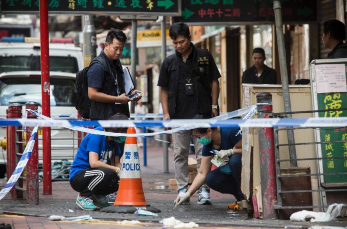 Police forensic officer (centre R) takes DNA swabs from a crime scene where police opened fire on a gang of men fighting in the Yau Ma Tei district of Hong Kong on Octopber 2, 2016. / AFP PHOTO / ISAAC LAWRENCE
