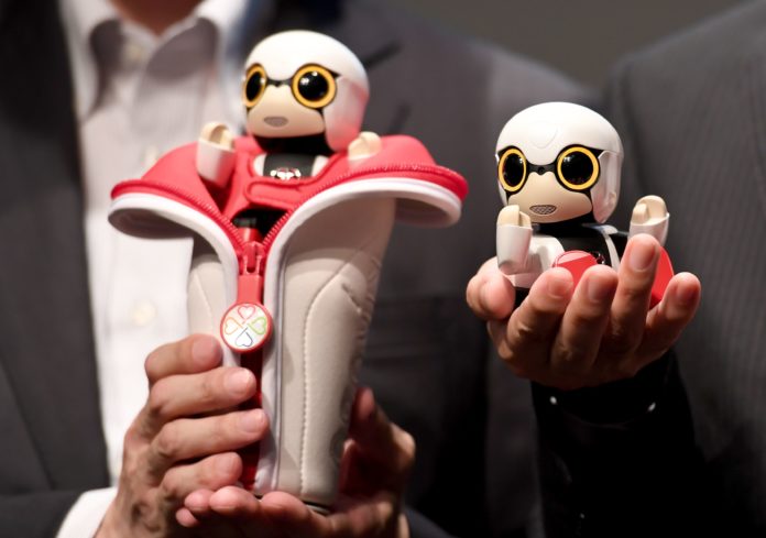 This picture taken on September 27, 2016 shows Toyota Motors new concept planning department project general manager Fuminori Kataoka (L) and president of the mid-size vehicle company and the senior managing officer of Toyota Motors Moritaka Yoshida (R) displaying the company's new communication robot 'Kirobo Mini' during a press preview in Tokyo. Equipped with artificial intelligence and a built-in camera, the robot is capable of recognising the face of the person speaking to him and responding in unscripted conversation or even starting a chat. / AFP PHOTO / TOSHIFUMI KITAMURA