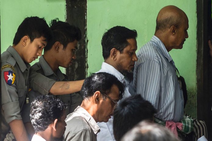 Defendants Hla Myint Oo (2nd R) and Khine Soe (R) are escorted by police after their court trial in Shwe Pyi Thar township in the outskirts of Yangon on October 10, 2016. Three Muslim men, including Hla Myint Oo and Khine Soe, went on trial in Myanmar on October 10 for illegally importing nearly 100 cows that have spent the last month under police protection, in a case Islamic leaders say targets their religion. / AFP PHOTO / ROMEO GACAD
