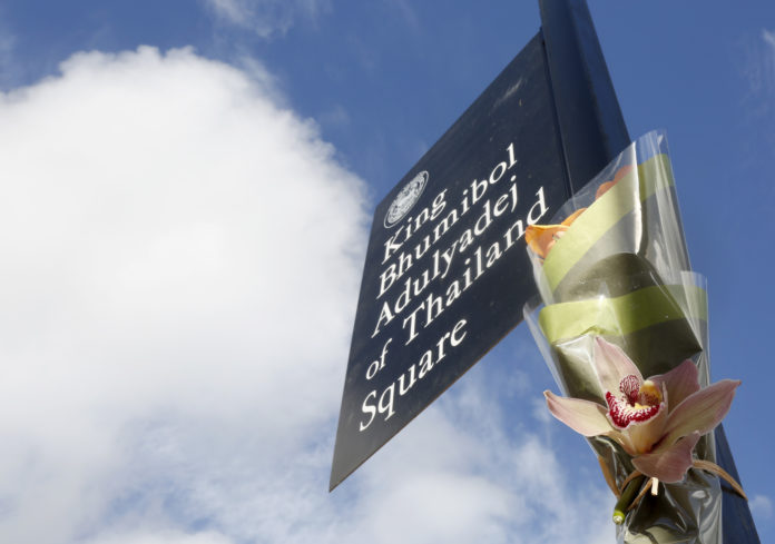 Flowers adorn a sign marking King Bhumibol Adulyadej Square / AFP PHOTO / Mary Schwalm