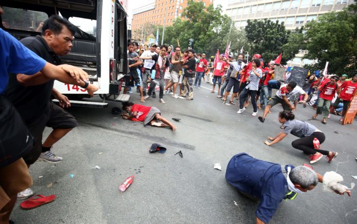 Protesters lie on the ground after being hit by a police van during a rally in front of the US embassy in Manila on October 19, 2016. A Philippine police van on October 19 rammed and ran over baton-wielding protesters outside the US embassy in Manila. / AFP PHOTO / STR