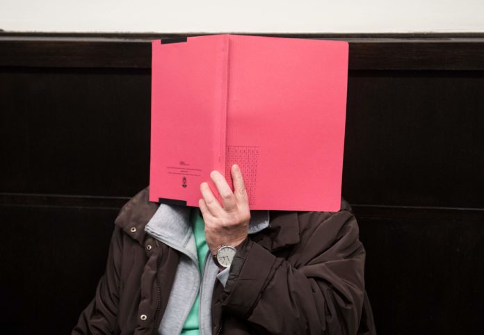 Defendant Angelika W covers herself in the courtroom of the regional court in Paderborn, western Germany, ahead the beginning of the trial, on October 26, 2016. The trial of a man and his ex-wife accused of kidnapping and mistreating eight women, two of them to death at their home in western Germany, opened in Paderborn. / AFP PHOTO / dpa / Bernd Thissen / Germany OUT