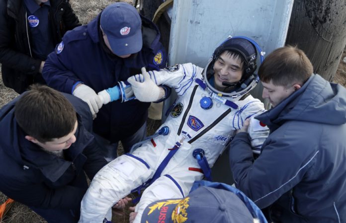 Ground personnel help International Space Station (ISS) crew member Japanese astronaut Takuya Onishi to get from the capsule shortly after the landing of the Russian Soyuz MS space capsule, about 150 kms (90 miles) southeast of the Kazakh town of Dzhezkazgan on October 30, 2016. Three astronauts landed safely in Kazakhstan on October 30 following a 115-day mission aboard the the International Space Station, including US astronaut Kate Rubins, the first person to sequence DNA in space. / AFP PHOTO / POOL / Dmitri Lovetsky