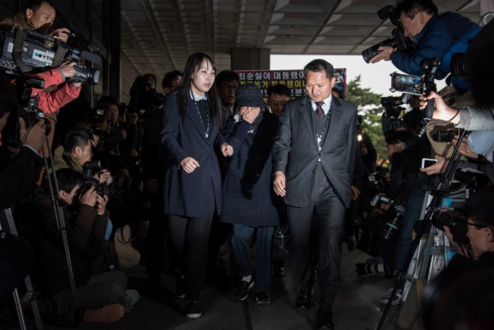 Choi Soon-Sil (C) is escorted as she arrives at the Seoul Central District Prosecutor's Office in Seoul on October 31, 2016. South Korean prosecutors questioned the woman at the centre of a political scandal that has shattered public confidence in President Park Geun-Hye, with allegations of fraud and meddling in state affairs. / AFP PHOTO / Ed Jones