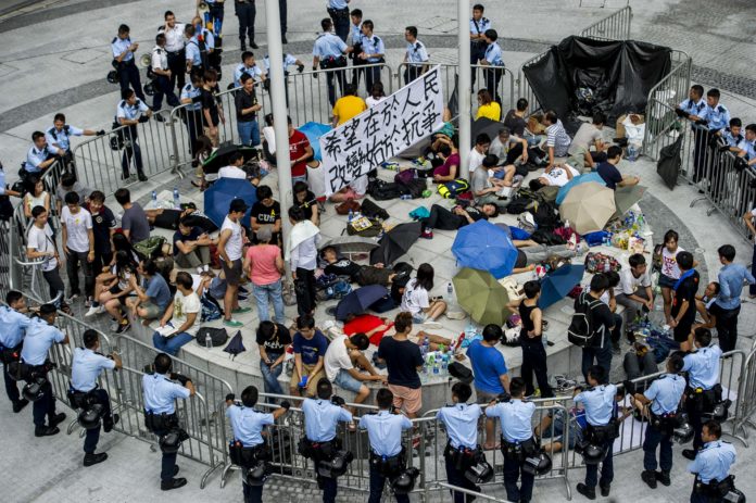 Protesters are surrounded by police after breaking through the gates of the Hong Kong government headquarters on September 27, 2014. Police cleared dozens of protesters who had been holding out at government headquarters on September 27 after storming the complex overnight, as a week-long protest against Beijing's refusal to grant the city unfettered democracy turned angry. AFP PHOTO / XAUME OLLEROS