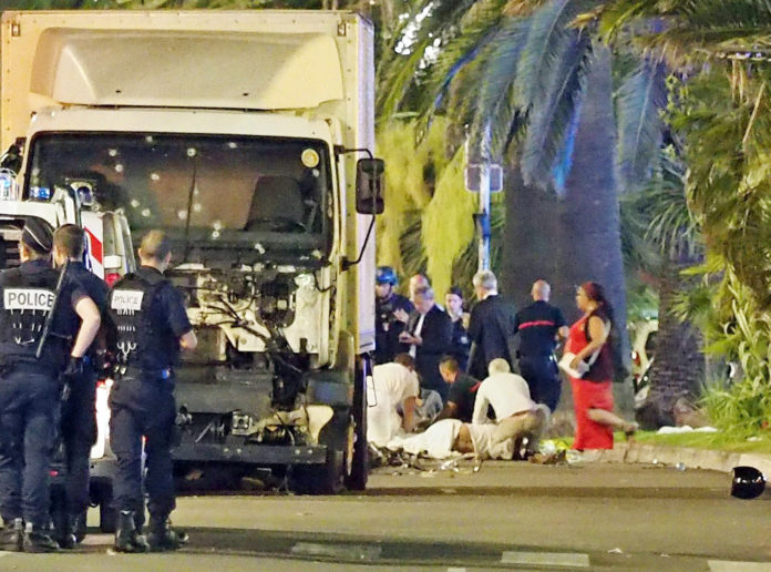 Police stand by as medical personnel attend a person on the ground, right, in the early hours of Friday, July 14, 2016, on the Promenade des Anglais in Nice, southern France, next to the lorry that had been driven into crowds of revelers late Thursday. France has been stunned again as a large white truck killed many people after it mowed through a crowd of revelers gathered for a Bastille Day fireworks display late Thursday evening, in the Riviera city of Nice. (AP Photo)