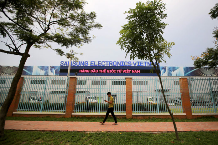 A pedestrian walks past the Samsung Electronics Vietnam Co. Plant at Yen Phong Industrial Park in Bac Ninh Province, Vietnam, on Thursday, Sept. 1, 2016. Samsung Electronics Co. and its affiliate have built a factory town with 45,000 young workers and hundreds of foreign component suppliers -- a miniature version of the family-run chaebol conglomerates that dominate business back in Korea. The investment has been a windfall for businesses in Bac Ninh -- almost 2,000 new hotels and restaurants opened between 2011 and 2015 according to the provincial statistics office -- helping raise the province's per capita GDP to three times the national average. Photographer: Linh Luong Thai/Bloomberg