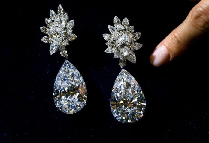 A picture taken on November 10, 2016 shows a model displaying a pair of diamond earrings called "Miroir de l'Amour" created from two D-color, flawless pear-shaped diamonds of 52,55 and 50,47 carats during a press preview at Christie's auction house in Geneva. The earrings were sold for USD 17,61 million during jewels sales in Geneva on November 15, 2016. / AFP PHOTO / FABRICE COFFRINI