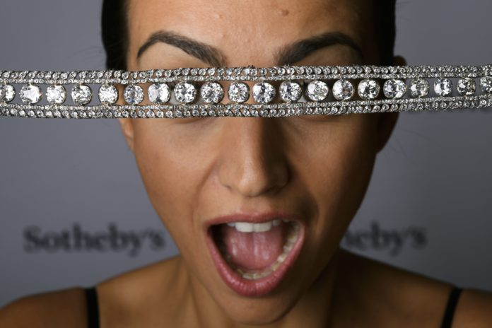 A model poses with a diamond necklace with a stunning and delicate bowknot clasp during a press preview by Sotheby's auction house on November 9, 2016 in Geneva. The historical necklace commissioned as two separate pieces by Empress Catherine II, known as Catherine the Great (1729  1796) will be offered at a 'Magnificent jewels & noble jewels auction' in Geneva on November 16, 2016 with a pre-sale estimate of US $3-5 million. / AFP PHOTO / FABRICE COFFRINI
