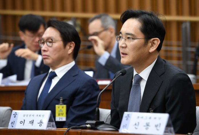 Samsung Group's heir-apparent Lee Jae-Yong (R) answers a question as SK Group chairman Chey Tae-Won (L) listens to during a parliamentary probe into a scandal engulfing President Park Geun-Hye at the National Assembly in Seoul on December 6, 2016. The publicity-shy heads of South Korea's largest conglomerates faced their worst nightmare on December 6, as they were publicly grilled about possible corrupt practises before an audience of millions. / AFP PHOTO / POOL / JUNG YEON-JE