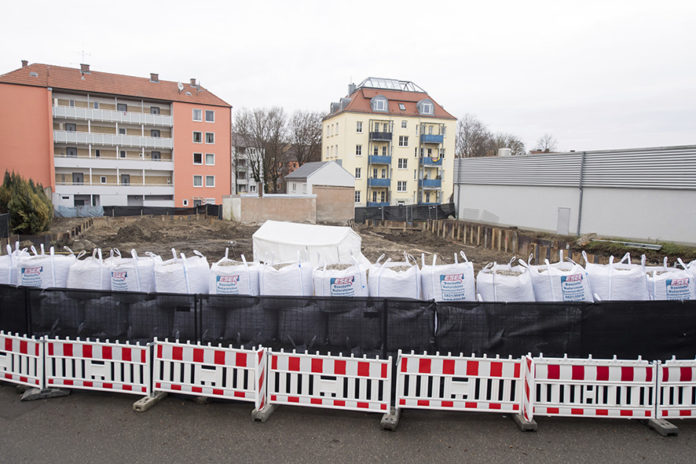 Sand bags and a fence are securing the location of the bomb site next to a construction site in Augsburg, Germany, Sunday Dec. 25, 2016. Thousands of people in the German town of Augsburg have temporarily left Christmas presents and decorations behind while authorities disarm a World War II bomb. The bomb was uncovered last week during construction work. (Tobias Hase/dpa via AP)