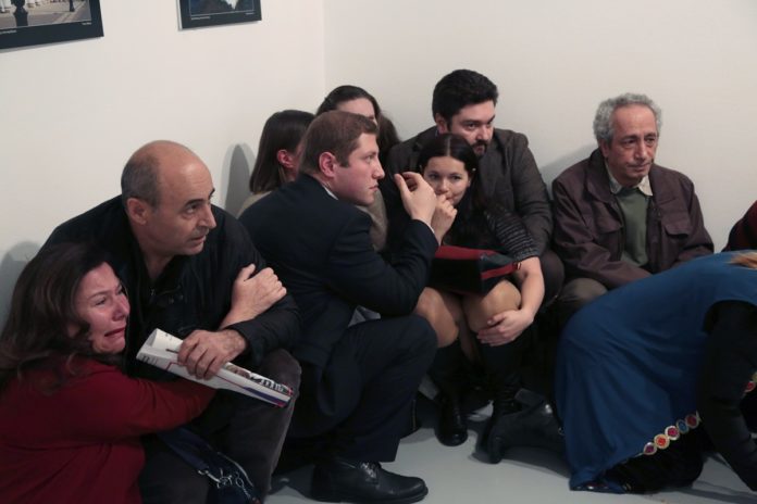 People crouch in a corner after Andrei Karlov, the Russian Ambassador to Turkey, was shot at a photo gallery in Ankara, Turkey, Monday, Dec. 19, 2016. Karlov, 62, was several minutes into a speech at an embassy-sponsored photo exhibition when a man fired a gun at him. Karlov was rushed to a hospital after the attack and later died from his gunshot wounds. (AP Photo/Burhan Ozbilici)