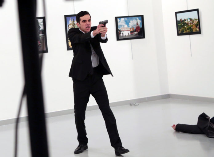 An unnamed gunman gestures after shooting the Russian Ambassador to Turkey, Andrei Karlov, at a photo gallery in Ankara, Turkey, Monday, Dec. 19, 2016. The Russian foreign ministry spokeswoman said he was hospitalized with a gunshot wound. (AP Photo/Burhan Ozbilici)