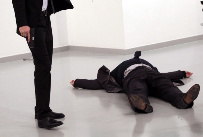 An unnamed gunman holds the gun after shooting the Russian Ambassador to Turkey, Andrei Karlov, at a photo gallery in Ankara, Turkey, Monday, Dec. 19, 2016. A gunman opened fire on Russia's ambassador to Turkey at a photo exhibition on Monday. The Russian foreign ministry spokeswoman said he was hospitalized with a gunshot wound. (AP Photo/Burhan Ozbilici)