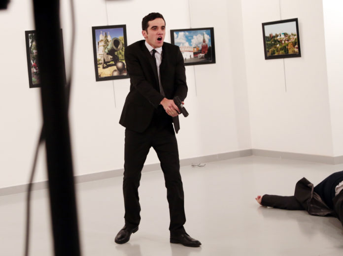 An unnamed gunman shouts after shooting the Russian Ambassador to Turkey, Andrei Karlov, at a photo gallery in Ankara, Turkey, Monday, Dec. 19, 2016. A Russian official says that the country's ambassador to Turkey has died after being shot by a gunman in Ankara. (AP Photo/Burhan Ozbilici)
