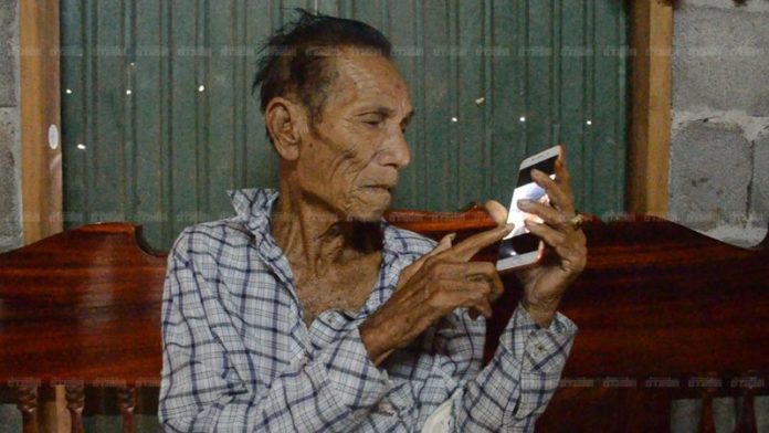 พ่อหนุ่มรักแท้นั่งดูรูปลูกชายจากโทรศัพท์มือถือ