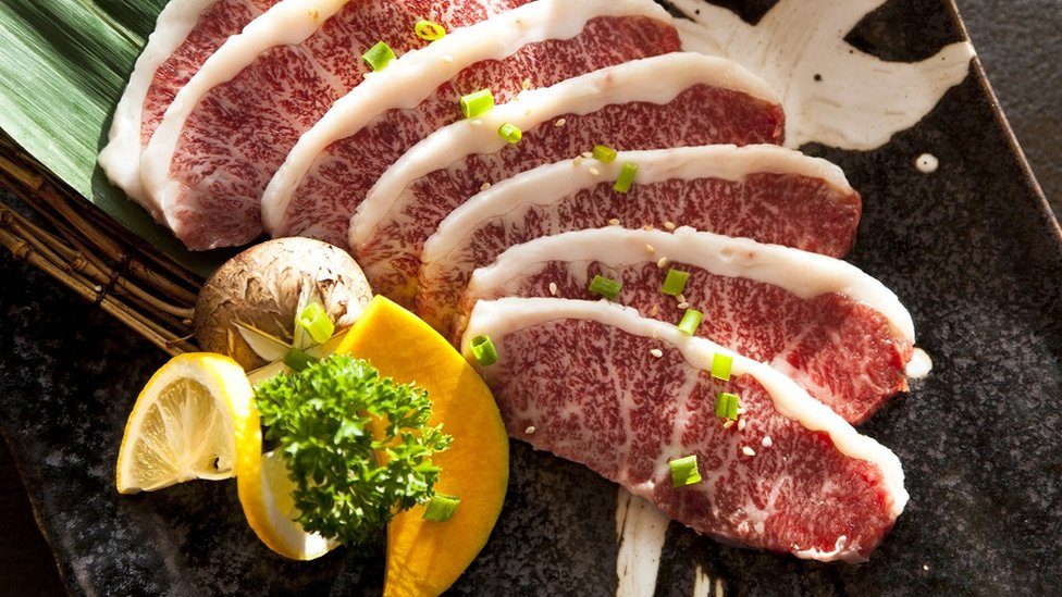 Wagyu Beef sliced decorated with a slice of lemon, on a plate on table