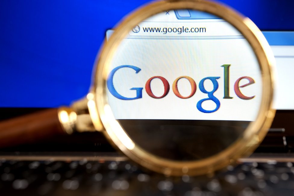 Close up to Google website through a magnifying glass on the laptop.