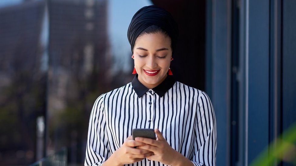 A young businesswoman using a smartphone on the balcony of a modern office building