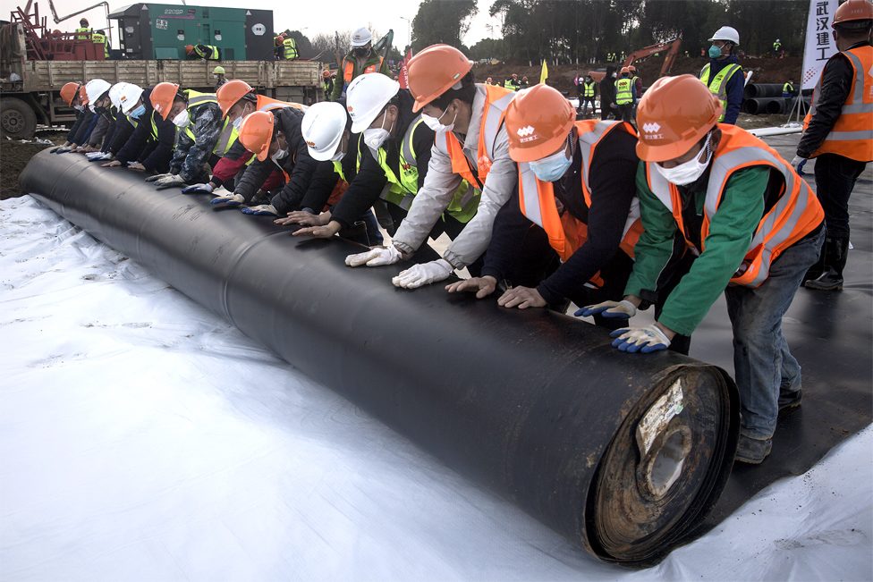 Construction workers roll out damp proof lining