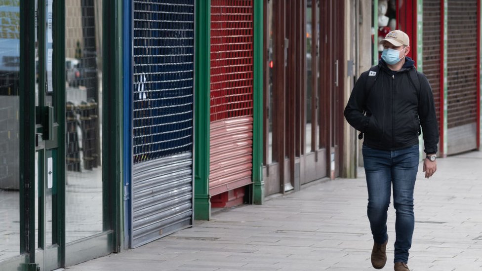 A man walking past closed shops