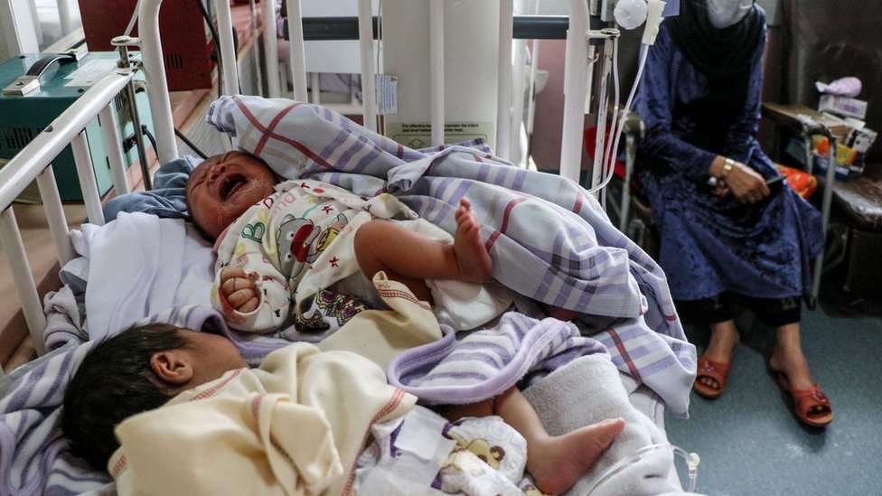 A woman (R) sits next to newborn babies who lost their mothers following a suicide attack in a maternity hospital, in Kabul on May 13, 2020
