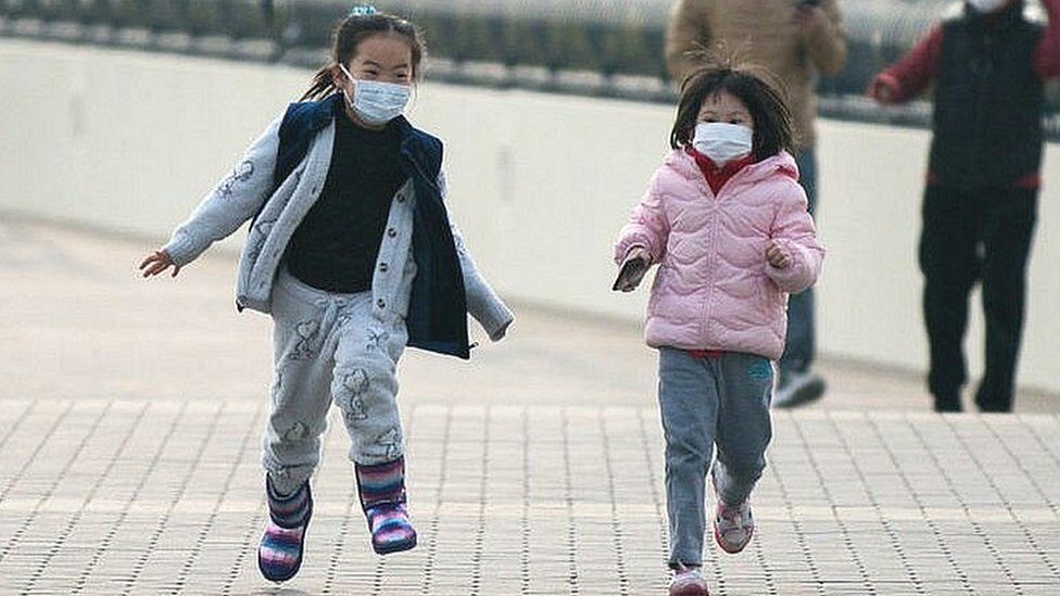 two little girls running wearing masks