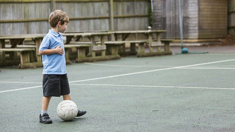 School boy playing on his own in playground