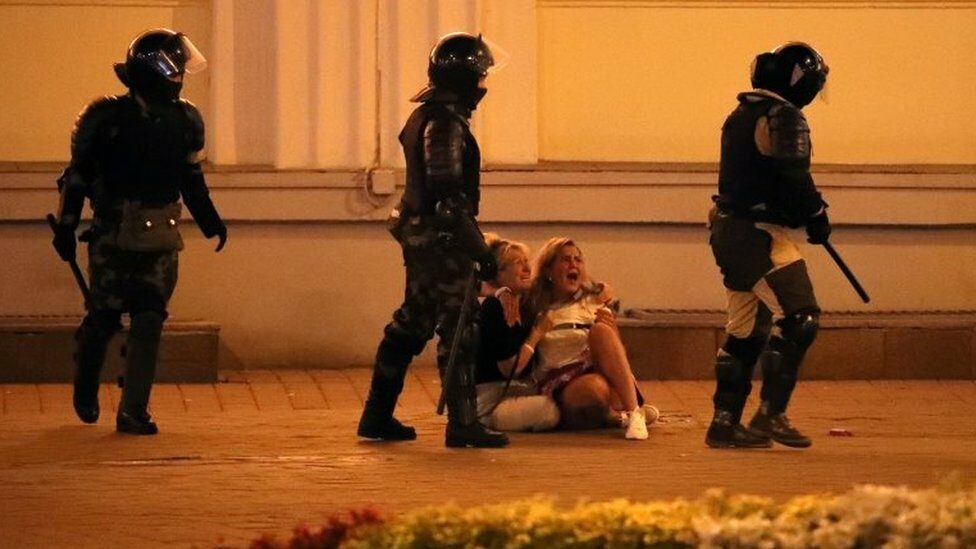 Riot police pass by two crying women during a protest the day after the presidential election, in Minsk, Belarus, 10 August 2020