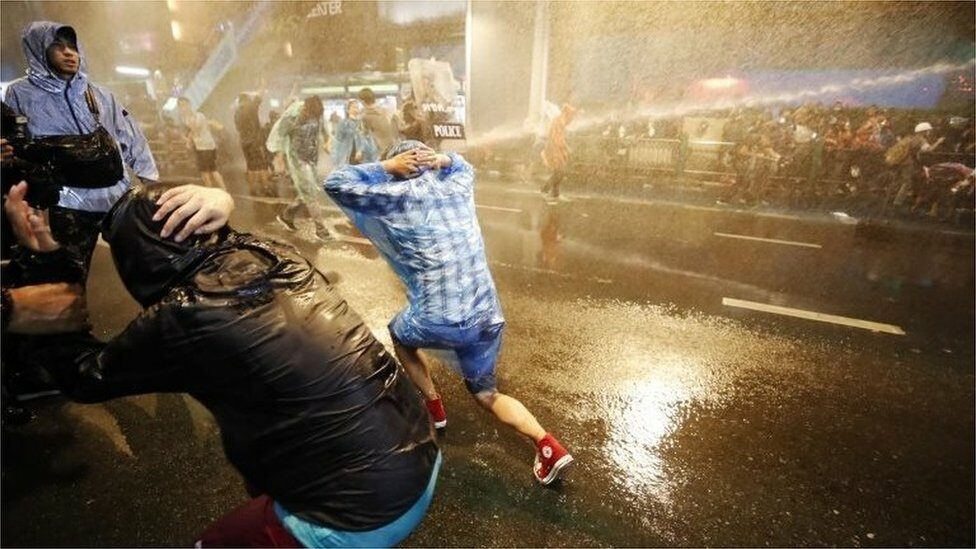 Pro-democracy protesters react as riot police fire water canons during an anti-government protest in Bangkok, Thailand, 16 October 2020