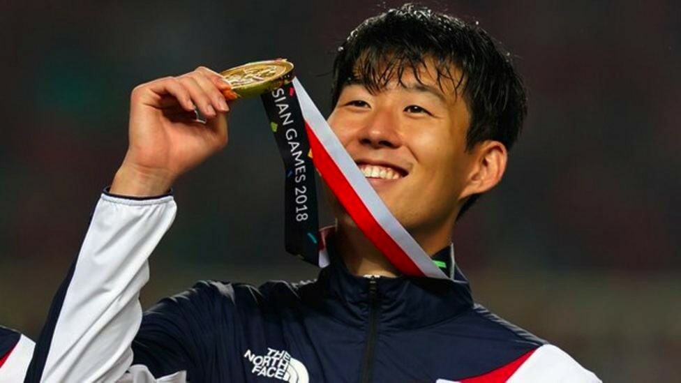 Son Heung-min holds aloft his gold medal,