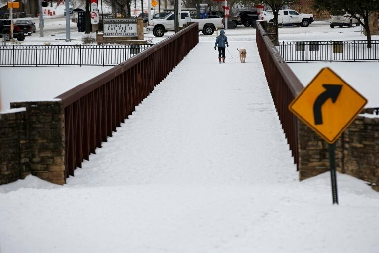 Anna Thomasson walks her dog, Penny, across the White Rock Lake Spillway after winter weather caused electricity blackouts in Dallas, Texas, U.S. February 18, 2021