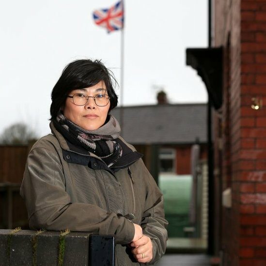 Jihyun Park stands in front of a house with a union flag flying in the background