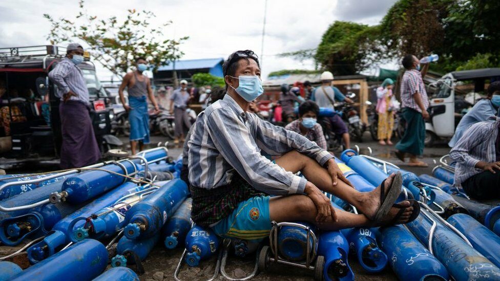 ผู้ชายนั่งบนถังออกซิเจนเปล่าในเมืองมัณฑะเลย์