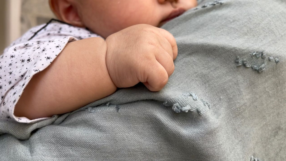 A baby holding onto its mother