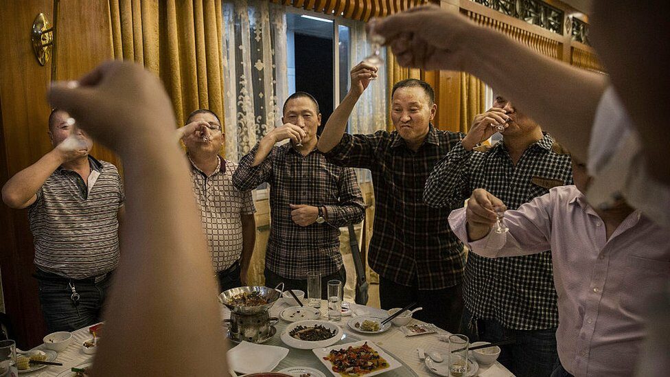 Chinese men toast each other and drink Moutai, the most famous wine called baijiu