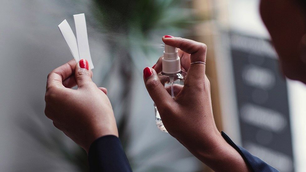 A person sprays a fragrance on scent cards