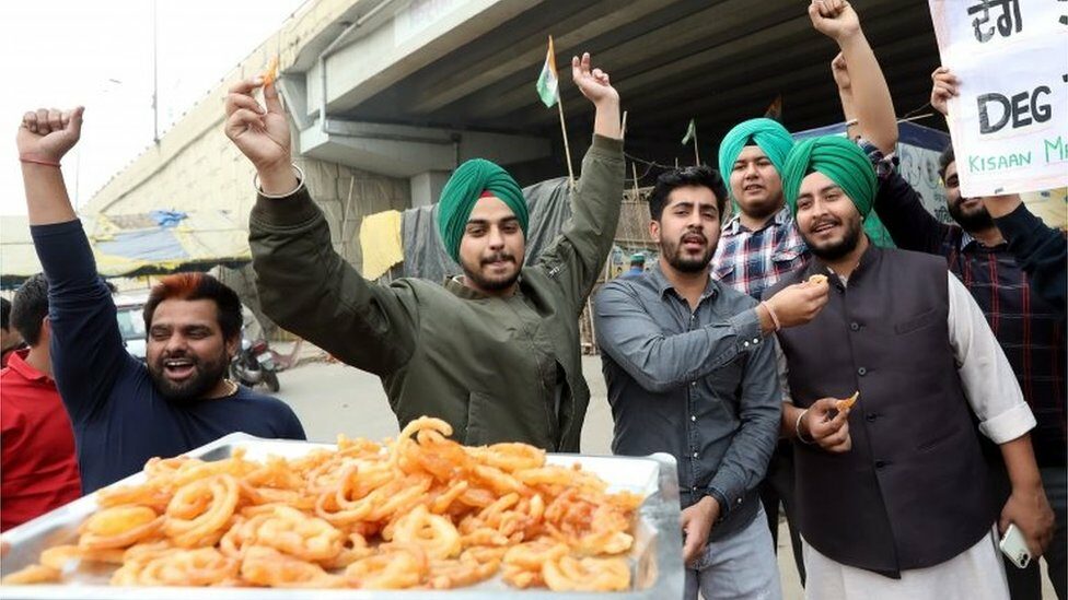 Indian farmers distribute sweets as they celebrate at the Delhi Uttar Pradesh Boarder, India, 19 November 2021.