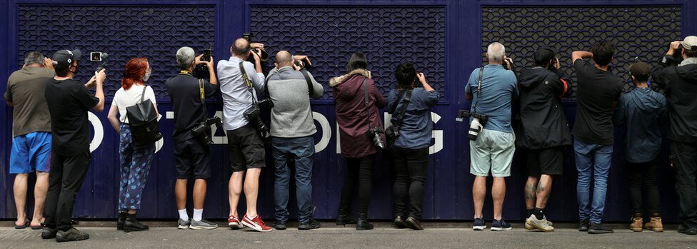 Photographers and videographers peer into a car park trying to get a glimpse of Serbian tennis player Novak Djokovic at the offices of his legal team
