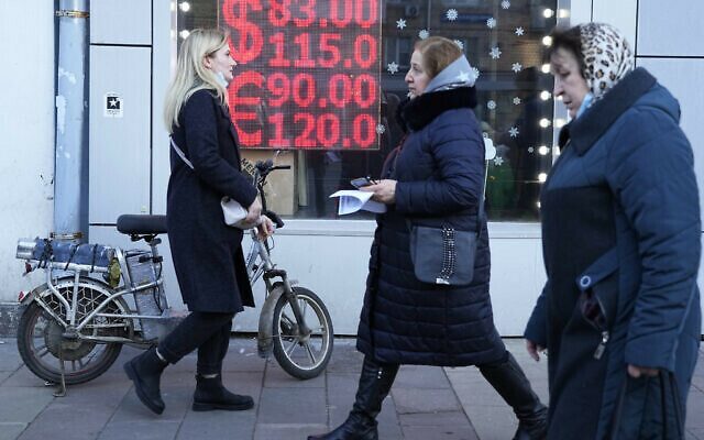 People walk past a currency exchange office screen displaying the exchange rates of U.S. Dollar and Euro to Russian Rubles in Moscow's downtown, Russia, Monday, Feb. 28, 2022. Ordinary Russians are facing the prospect of higher prices as Western sanctions over the invasion of Ukraine sent the ruble plummeting. That's led uneasy people to line up at banks and ATMs on Monday in a country that has seen more than one currency disaster in the post-Soviet era. (AP Photo/Pavel Golovkin)
