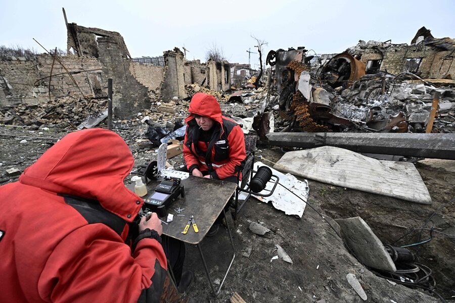 Repairmen restore local communication cables among the debris of destroyed armoured vehicles and buildings on a street in the town of Bucha.