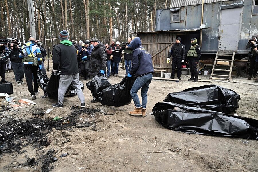 City workers carry body bags with six partially burnt bodies found in the town of Bucha.