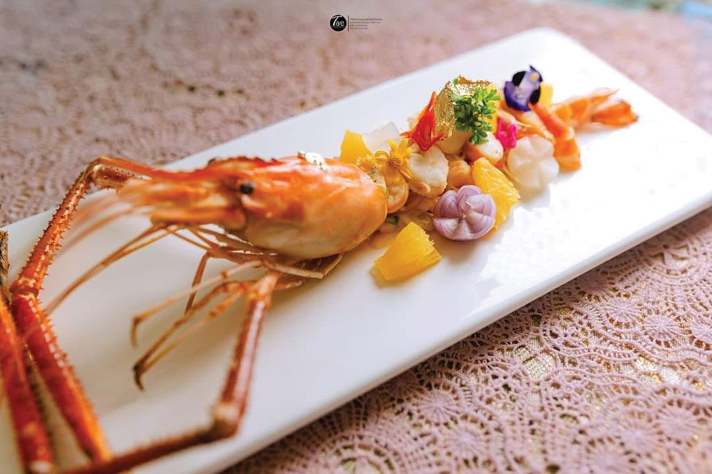  หากกล่าวถึง ร้านอาหารสไตล์เชฟเทเบิล หลายคนคงจะนึกถึงเมนูอาหารญี่ปุ่น หรืออาหารสไตล์ยุโรปสุดหรู ที่รังสรรค์โดยเชฟมากฝีมือที่มาในราคาแพงหูฉี่  แต่สำหรับ ‘ร้านขนมอมยิ้ม’ กาญจนบุรี เป็นร้านอาหารไทยสไตล์เชฟเทเบิล ร้านแรกและร้านเดียวในจ.กาญจนบุรี มี เชฟแมนนี่ ผู้ซึ่งมีความเชี่ยวชาญด้านอาหารไทยและขนมไทย รับหน้าที่เป็นทั้งเจ้าของร้านและเชฟประจำร้าน