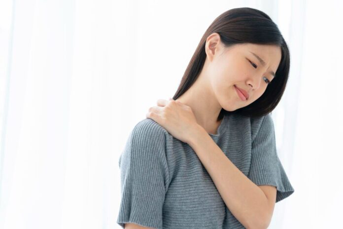 ผู้หญิงผมยาวเอามือจับไหล่ตัวเอง