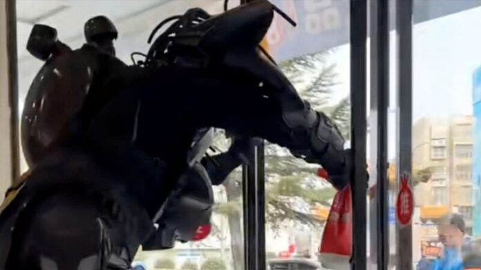 A curious passer-by, far-right, looks on as Zhou leaves the shop wearing his exoskeleton.