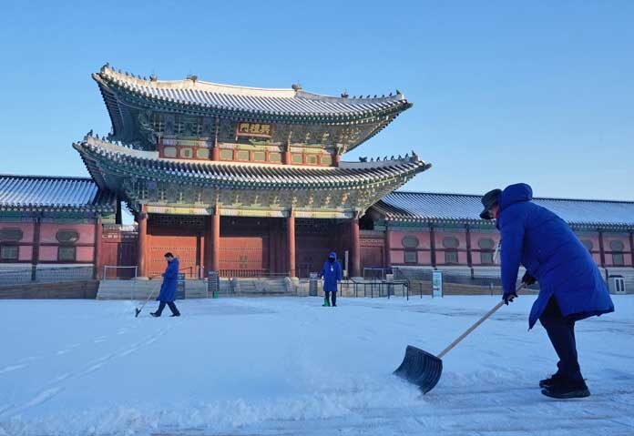 ประชาชนกำลังกวาดหิมะออกจากบริเวณด้านนอกพระราชวังคยองบกกุงในกรุงโซล ประเทศเกาหลีใต้ เมื่อวันศุกร์ที่ 5 ธันวาคม 2025