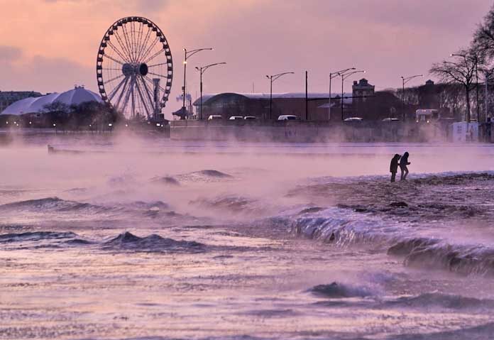 ผู้คนเดินบนชายหาดที่ปกคลุมด้วยน้ำแข็งริมชายฝั่งทะเลสาบมิชิแกน เมื่อวันศุกร์ที่ 23 มกราคม 2026 ในชิคาโก