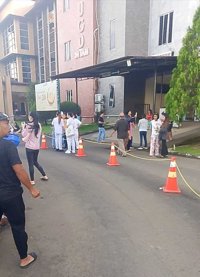 ภาพนี้แสดงผู้คนยืนอยู่ด้านนอกอาคารโรงพยาบาลหลังจากอพยพผู้คนออกไปเนื่องจากเกิดแผ่นดินไหวในเมืองมานาโด จังหวัดสุลาเวซีเหนือ ประเทศอินโดนีเซีย เมื่อวันที่ 2 เมษายน 2569